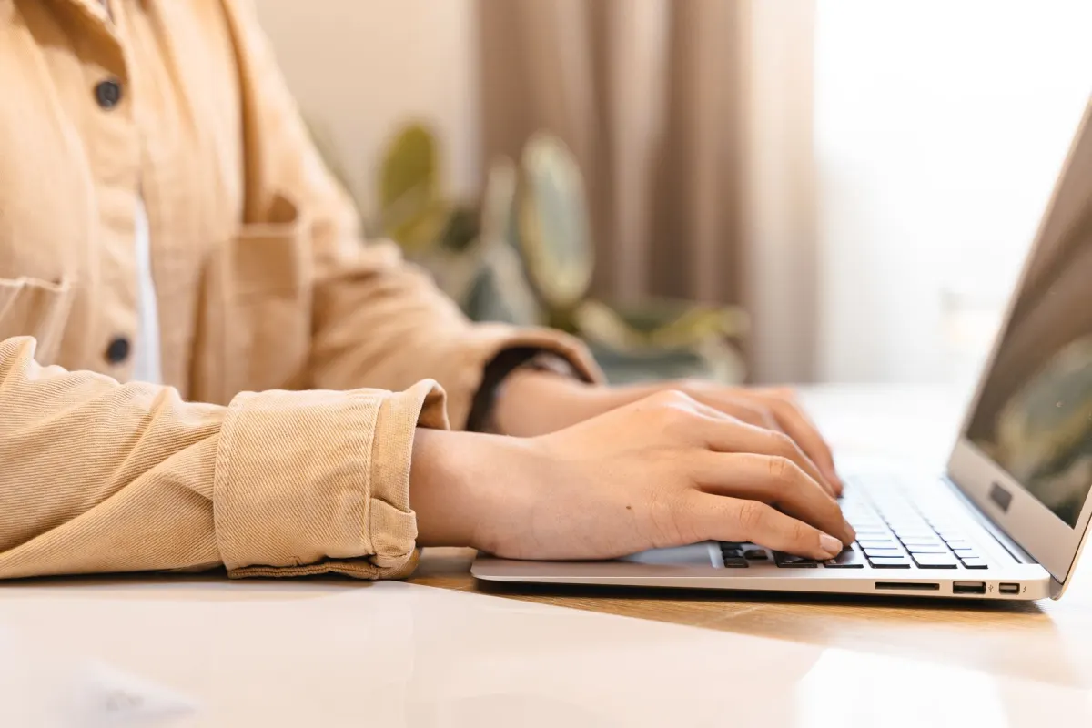 Una persona escribe en el teclado de un portátil en un escritorio, el tipo de uso cotidiano de escritorio donde la fuente del sistema de un ordenador cumple su función discretamente.