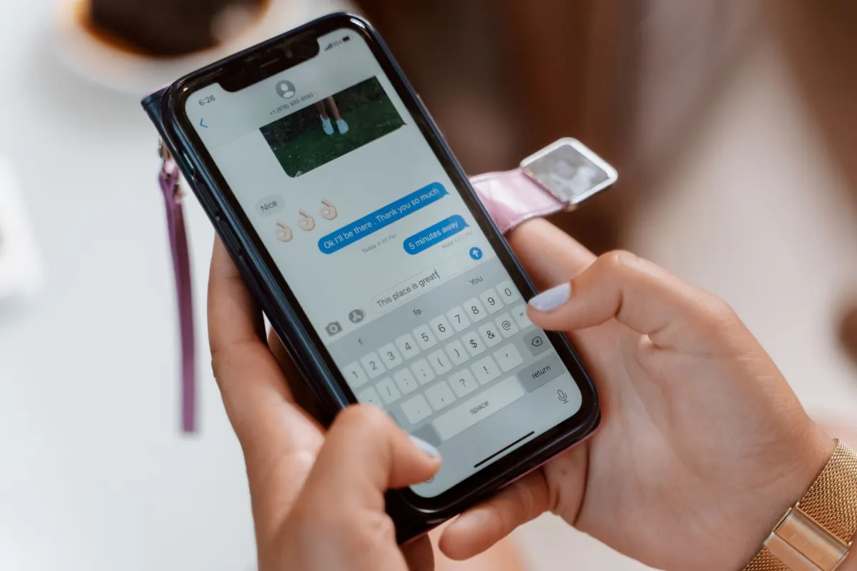 Une personne tape sur son téléphone en choisissant des emoji pour une publication.