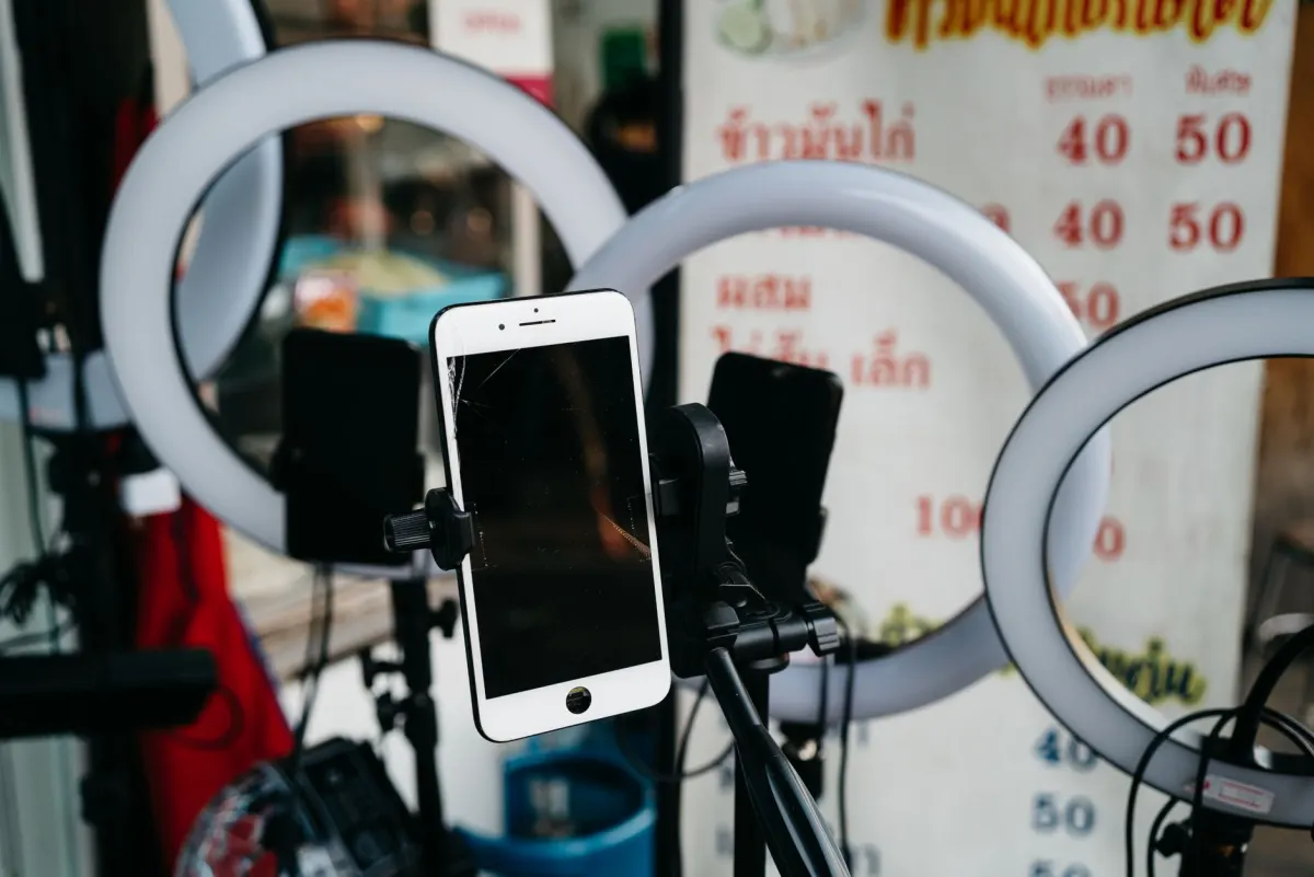 Eine Content-Erstellerin baut Ringlicht und Smartphone auf einem Stativ auf, um einen Live-Shopping-Stream aufzunehmen.