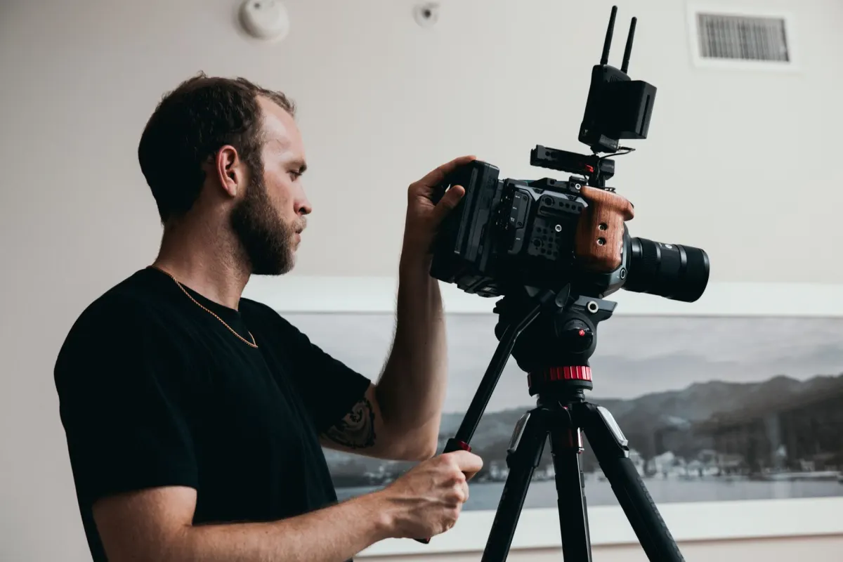 Um cinegrafista filma com uma câmera montada em um tripé, ao lado de uma visão geral de diferentes formatos de marketing de vídeo.