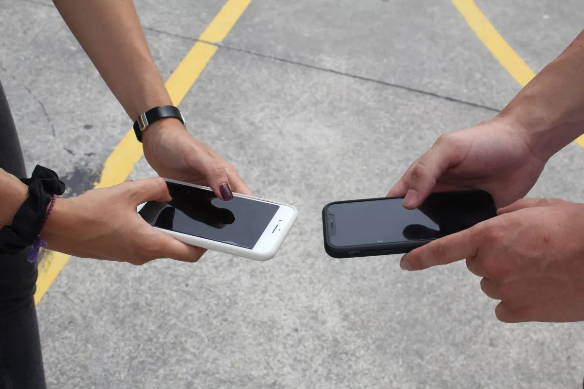 Zwei Personen schauen gemeinsam auf ein Smartphone, was zeigt, was es bedeutet, einen Beitrag an jemand anderen weiterzugeben.