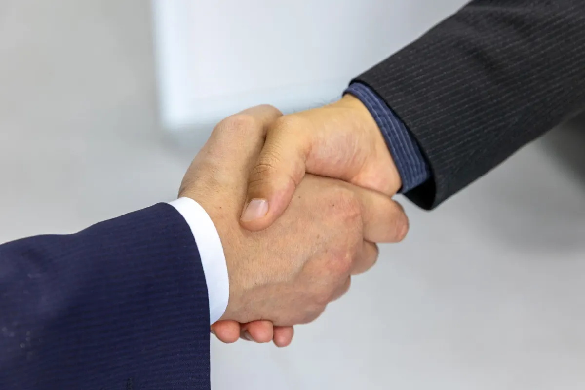 Deux personnes se serrent la main après une réunion, le moment où un nouveau client accepte de collaborer.
