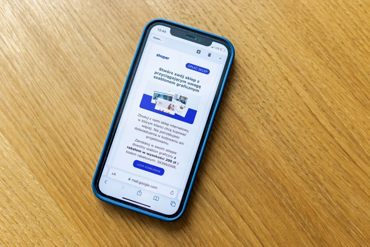 Una persona de marketing revisa una landing page en el teléfono junto a una laptop mientras prueba el flujo de registro.