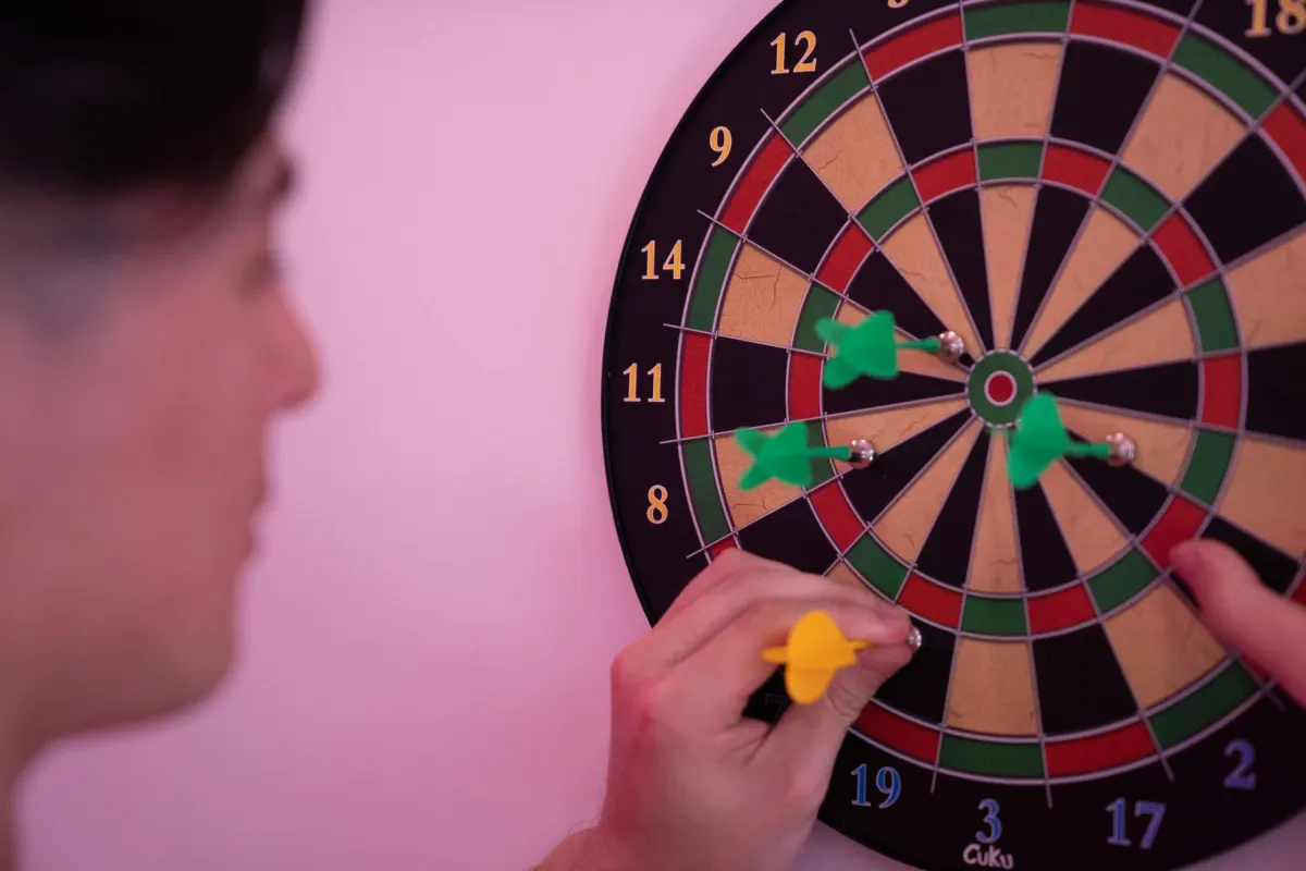 Eine Person wirft Darts auf eine Zielscheibe, ein Bild für die Präzision, die besseres Targeting in Werbekampagnen bringt.