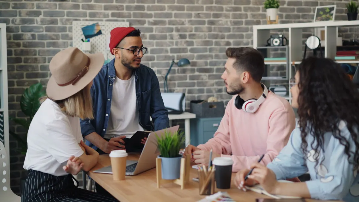 Coworkers gathered around an office table, illustrating a team change that removes someone's role on a Page.