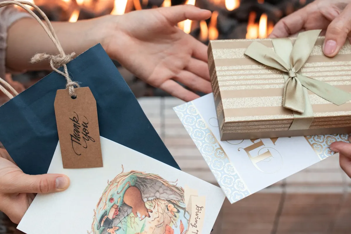 Una mujer entrega una tarjeta de regalo a una amiga, un ejemplo de la recompensa por referir que impulsa un programa de referidos.