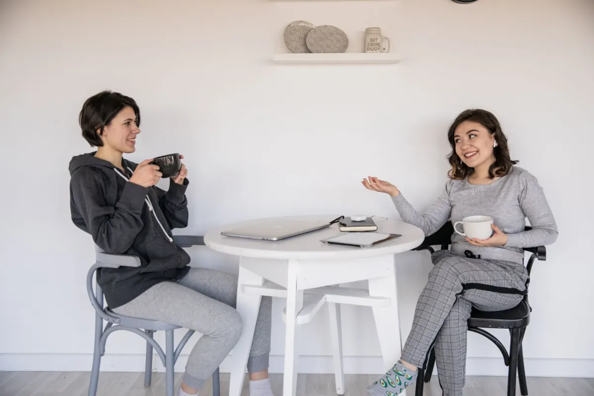 Deux personnes se retrouvent autour d'un café avec un ordinateur portable ouvert, illustrant l'étape de construction de relations derrière un Collab réussi.