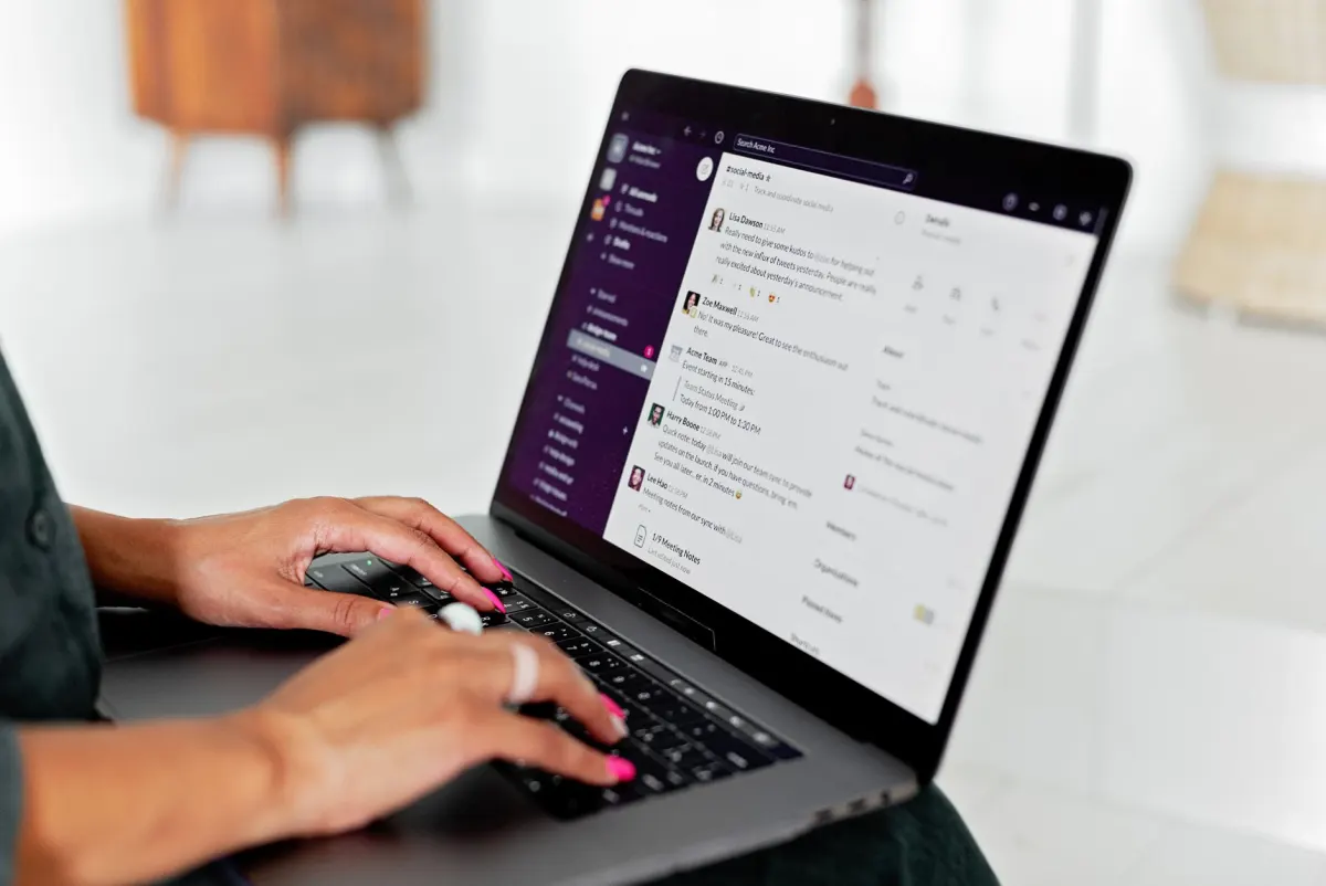 A person types on a laptop while chatting through a messaging app, illustrating everyday use of a connected assistant.