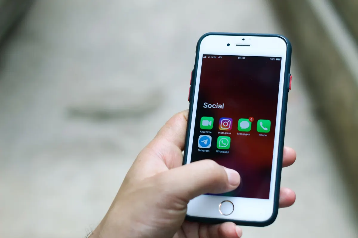 Una mano sostiene un teléfono con una app de mensajería abierta, el tipo de interfaz usada para hablar con un agente siempre activo.