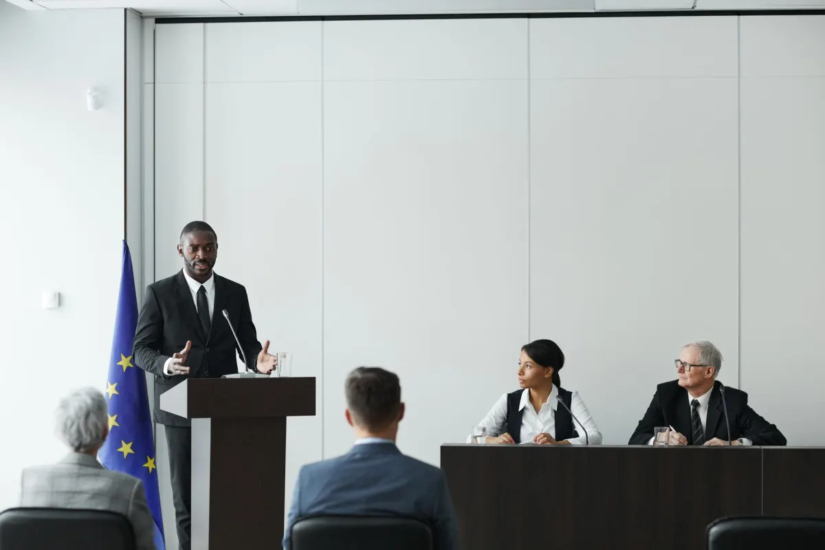 Autoridades sentadas à mesa revisam documentos, uma imagem do debate político sobre o que uma proibição de publicidade direcionada realmente abrangeria.