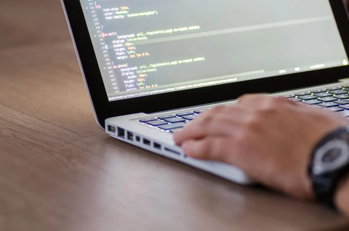 Un développeur web examine du code sur un ordinateur portable, comme le fait un propriétaire de site pour repérer les requêtes publicitaires sur ses pages.