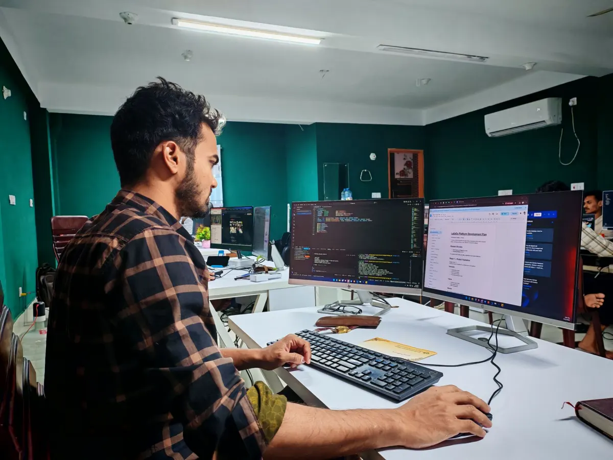 Un desarrollador trabaja en un escritorio con dos monitores, representando al ingeniero que convierte un problema detectado en una corrección.
