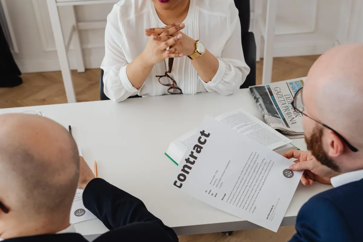 Kollegen besprechen an einem Tisch einen Vertrag, die Art von Anbieterprüfung, die Datenweitergabe-Vereinbarungen eines Unternehmens in Ordnung hält.