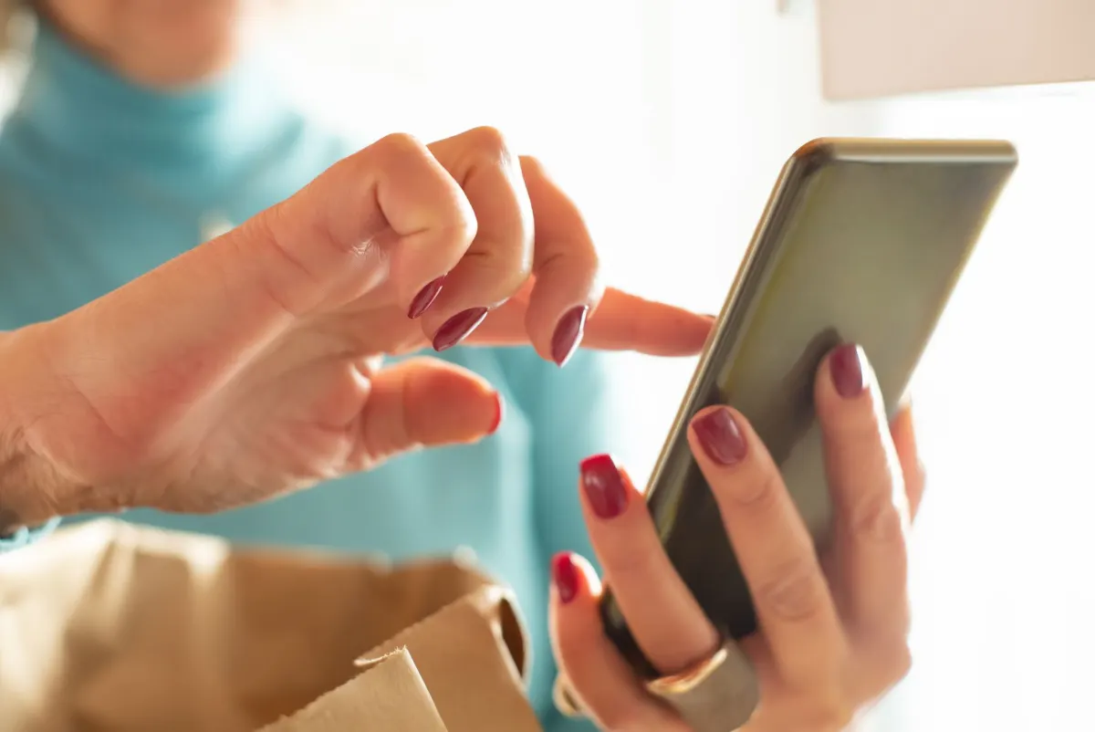 A visitor taps a phone screen while a product grid loads, the kind of laggy interaction that pushes INP into the poor range.