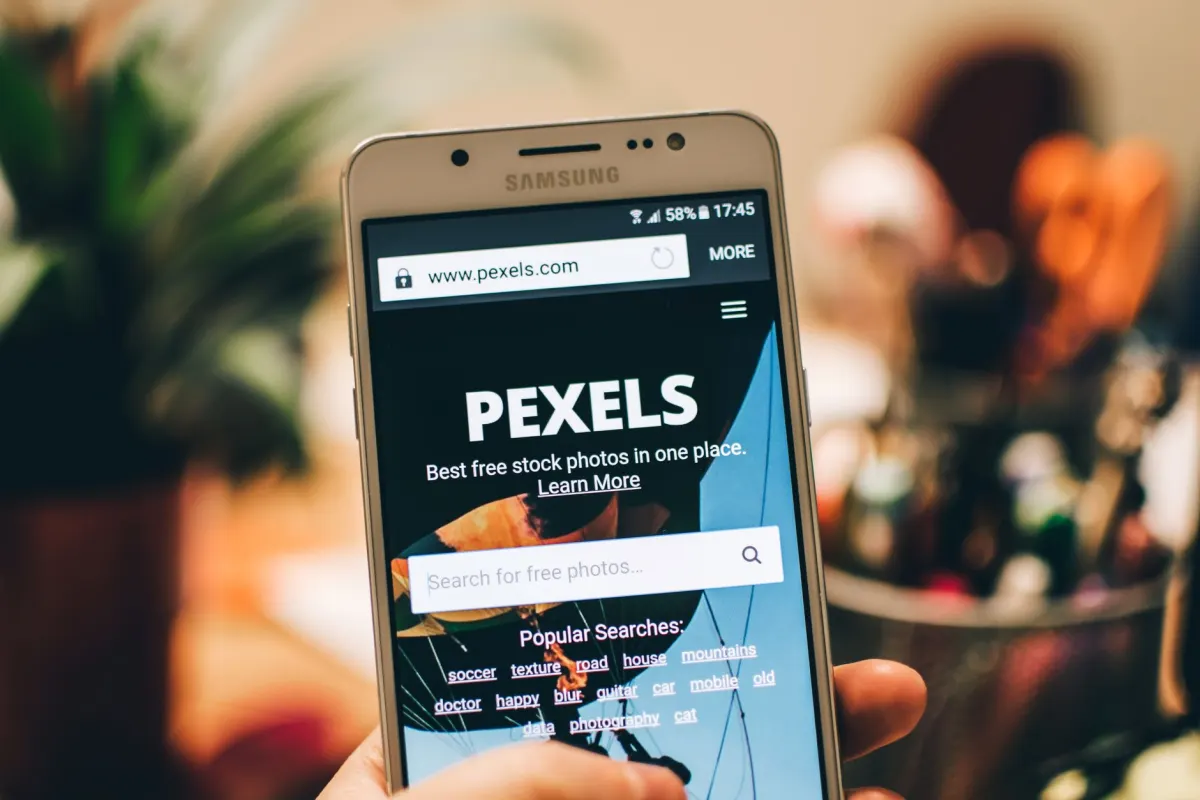 Eine Person scrollt auf einem Smartphone durch eine Website, was zeigt, wie dieselbe Seite auf Mobilgeräten anders dargestellt wird als auf dem Desktop.