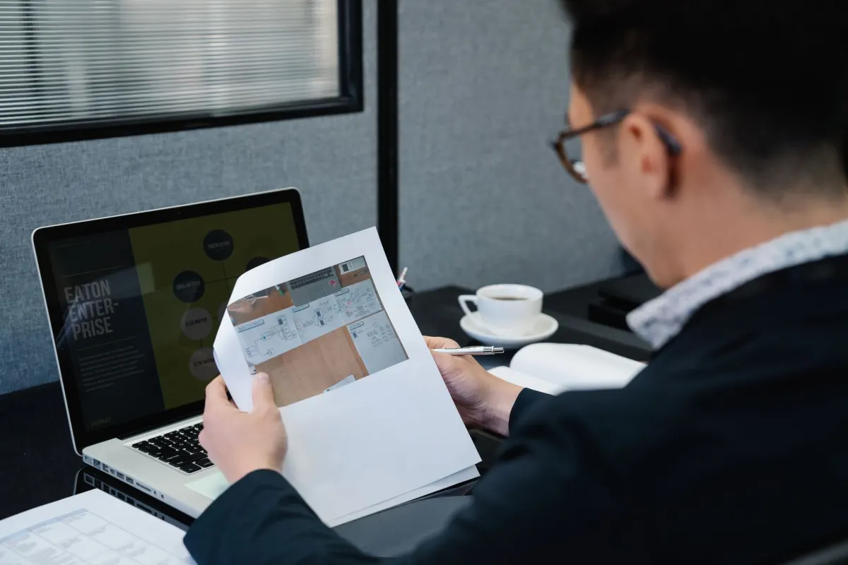 A person reads a weekly report on a laptop with a coffee, matching the Monday traffic summary workflow.