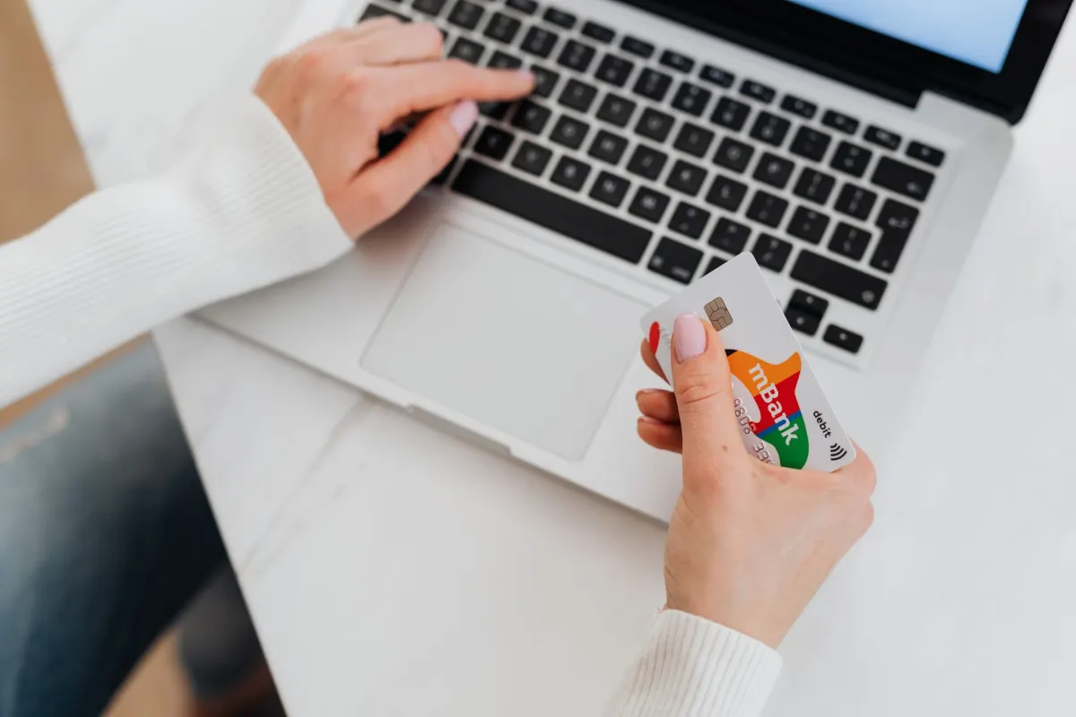 Una mujer introduce los datos de su tarjeta de crédito mientras compra en línea, lo que ilustra cómo la confianza influye en las decisiones de compra.