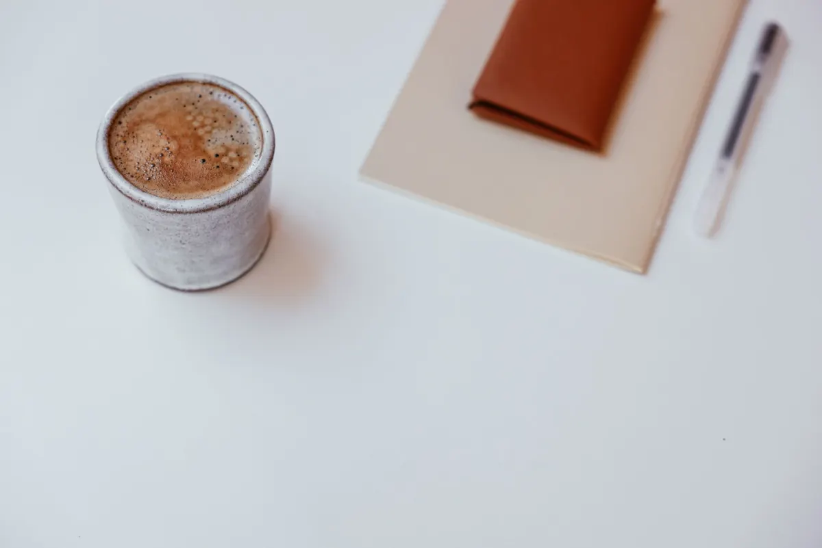 A notebook and coffee on a desk at the start of the workday, matching the weekday morning triage routine.