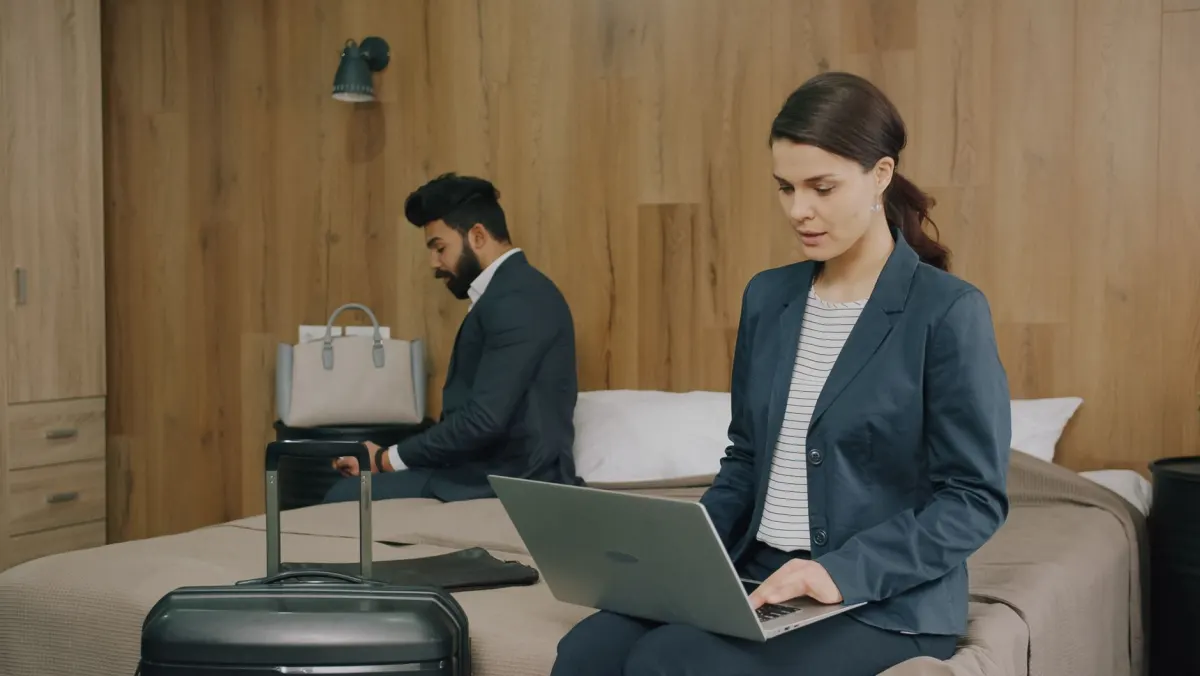 Une voyageuse attend sur son téléphone avec un wifi d'hôtel lent, la condition réelle que le RUM capture et qu'un test en laboratoire ne peut pas.