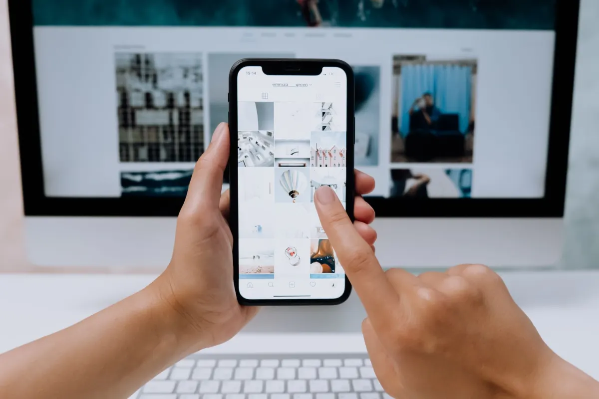 Ein Tester prüft eine Website auf einem iPhone neben einem Laptop, genau die Art von Vergleichstest, die diese Safari-Checkliste beschreibt.