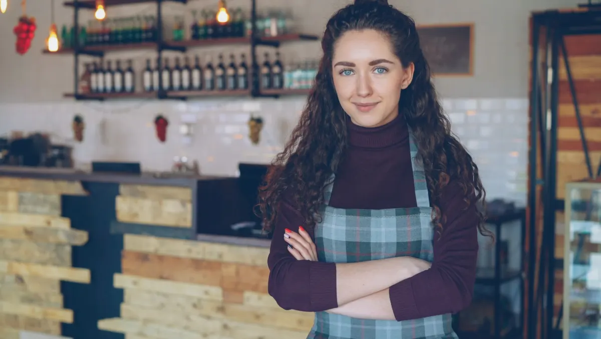 Un pequeño empresario trabaja con su portátil en una cafetería, una imagen de las necesidades más simples que una herramienta de analítica sin cookies puede cubrir sin un proxy del lado del servidor.