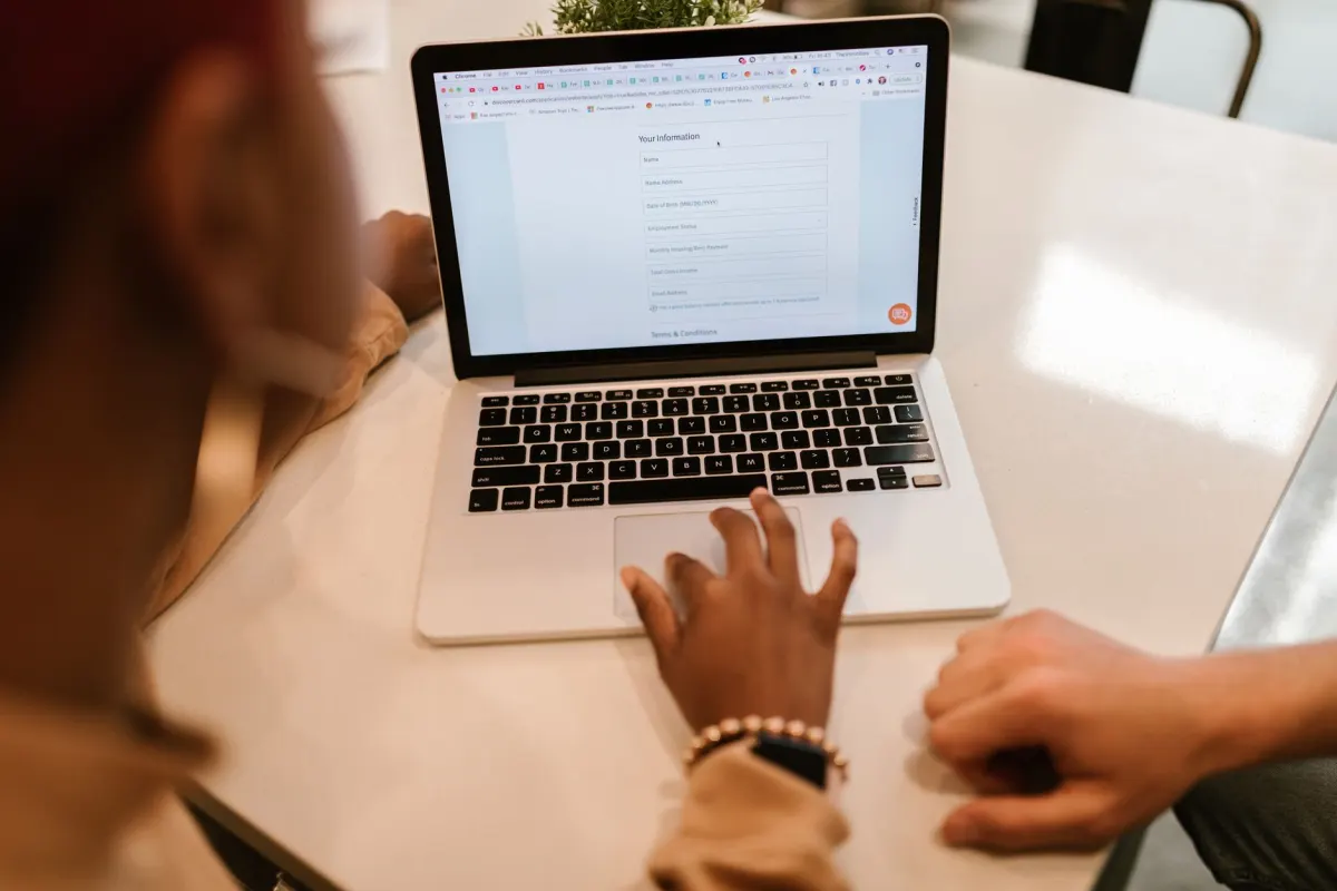 Une personne remplit un court formulaire en ligne sur un ordinateur portable, au moment où un téléchargement protégé demande des informations avant de le débloquer.