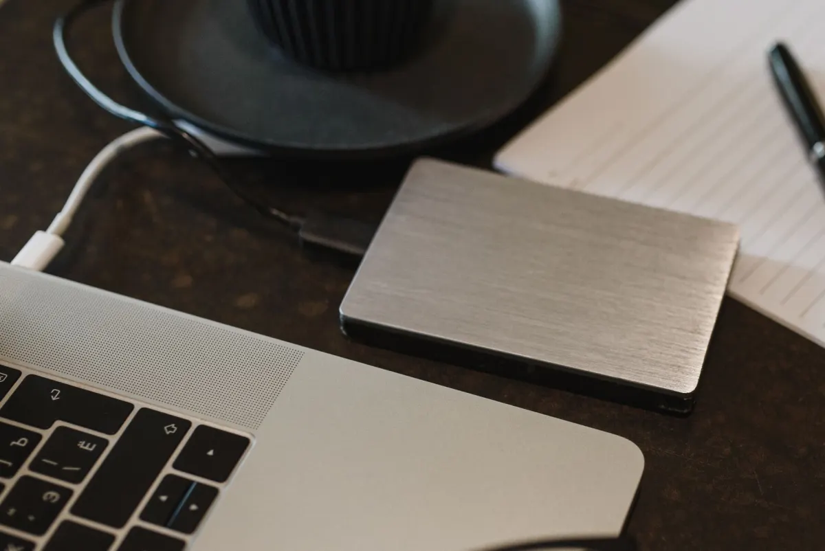 Um laptop conectado a um disco rígido externo, ilustrando a prática de exportar e fazer backup de dados de analytics.