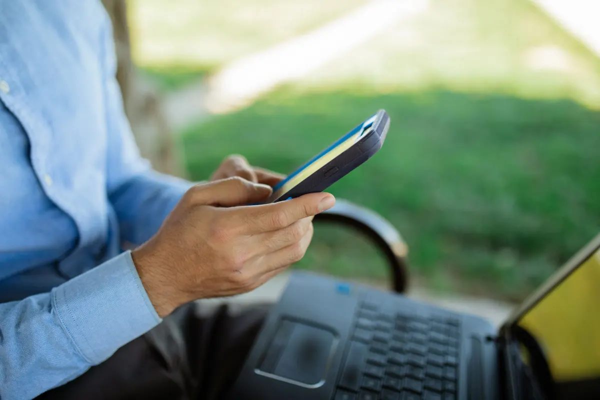 Eine Person prüft eine Website nebeneinander auf Smartphone und Laptop, um das Verhalten auf verschiedenen Geräten zu testen.