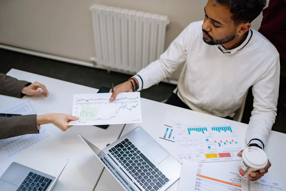 Two colleagues review traffic charts together on a laptop in an office setting.