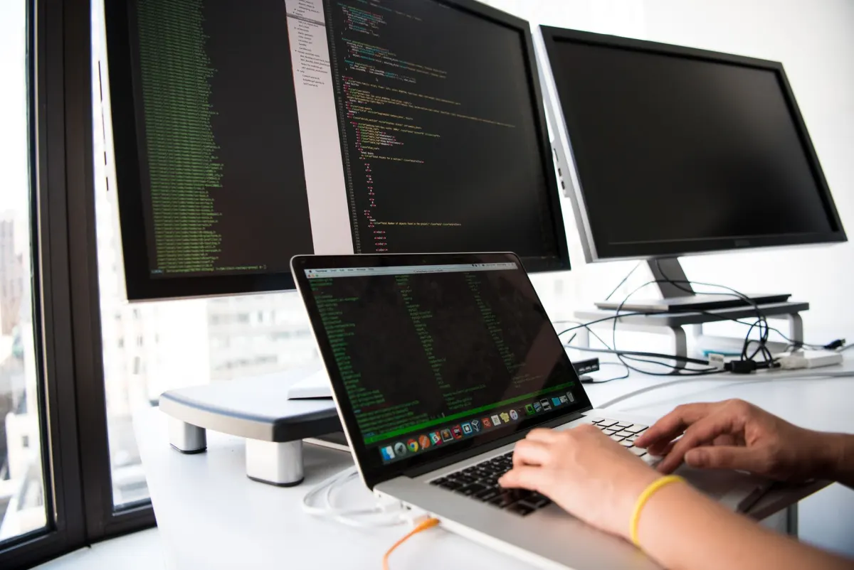 Two developers work at multi-monitor desks reviewing product usage data.