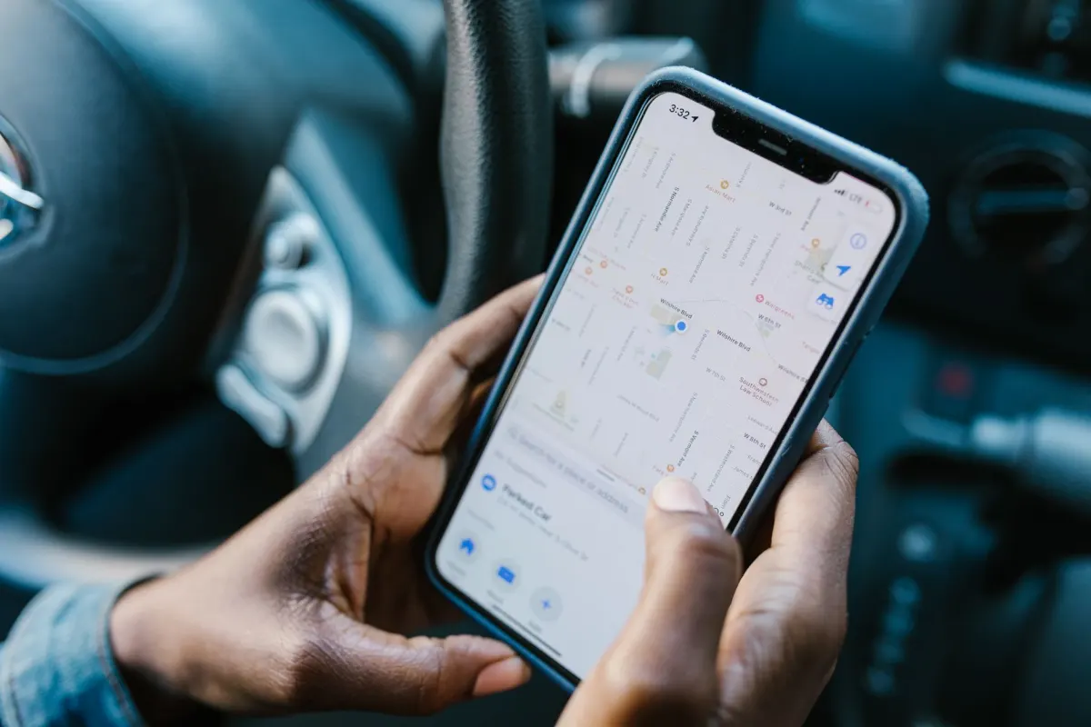 Eine Person konsultiert beim Gehen auf einer Stadtstraße ihr Smartphone für Wegbeschreibungen, was zeigt, wie im Alltag Standortdaten entstehen.