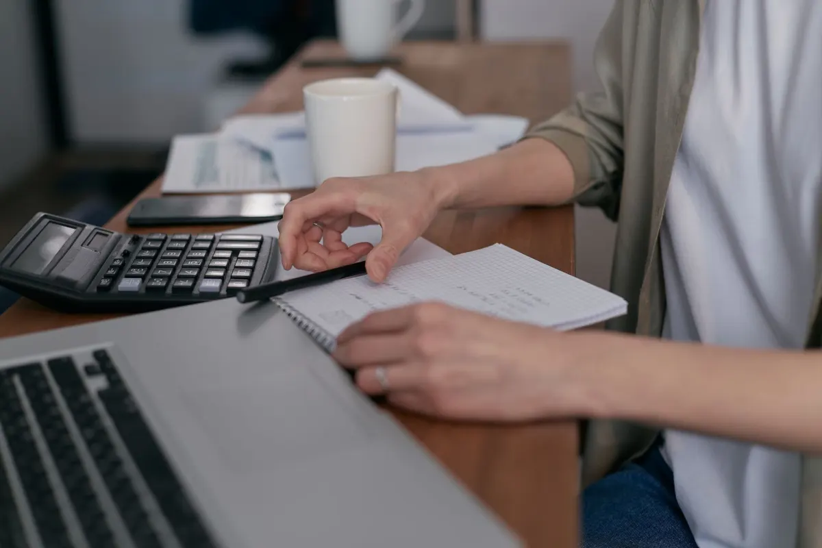 A small business owner going through paper invoices at a desk, representing sales that happen outside the website and still need to be recorded.