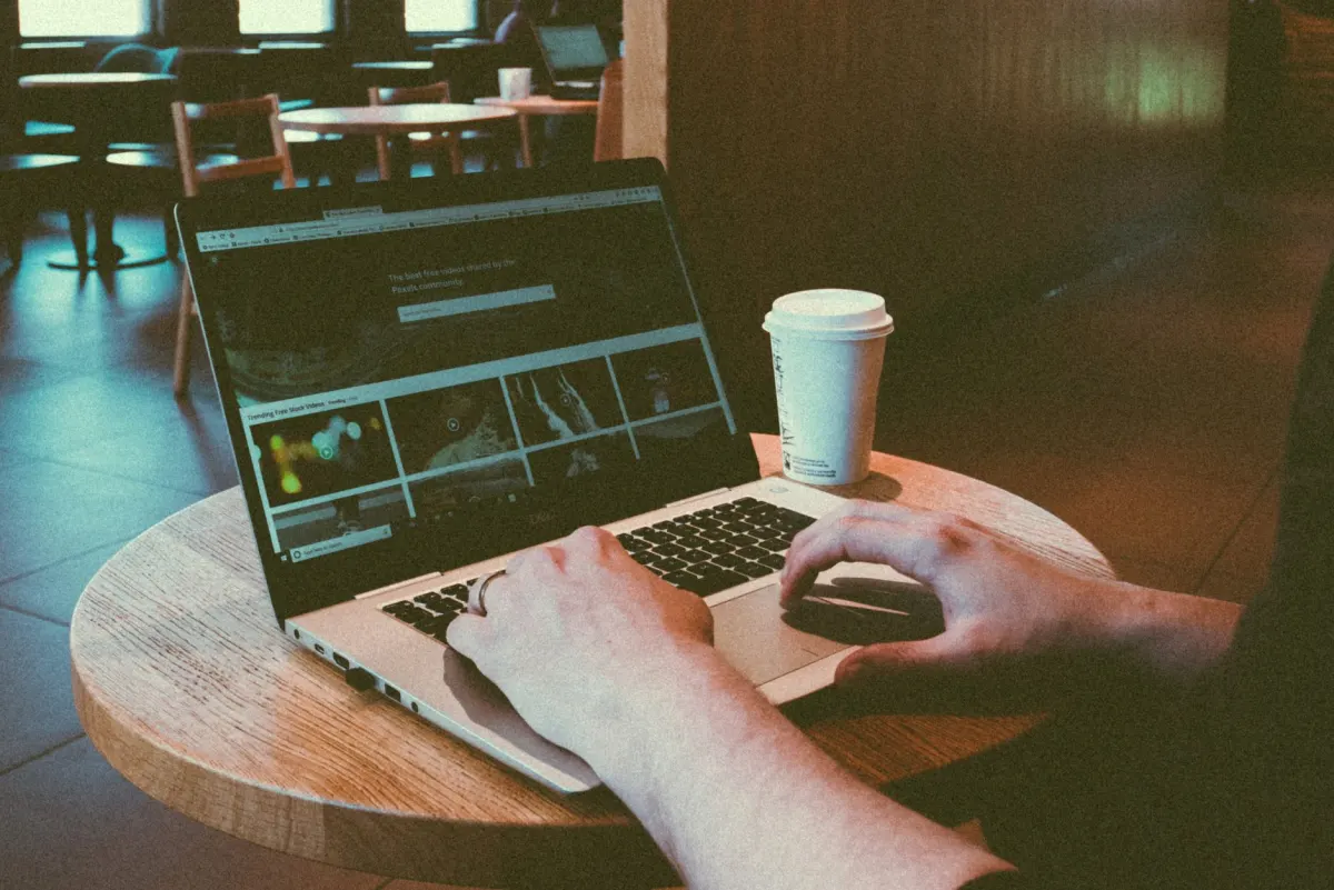Jemand tippt eine Antwort auf einem Laptop in einem Café, die alltägliche Szene hinter einem echten Community-Forenbeitrag.