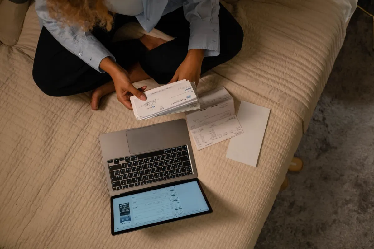 A person cross-checks a printed page against a laptop screen, the fact-correction work a team does after finding a hallucinated claim.