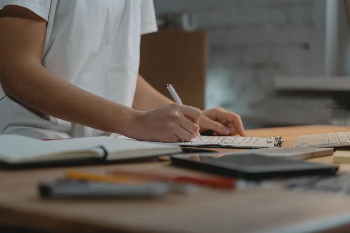 Une main cochant des éléments sur une liste de contrôle papier à un bureau, en écho à la vérification préalable décrite dans cette section.
