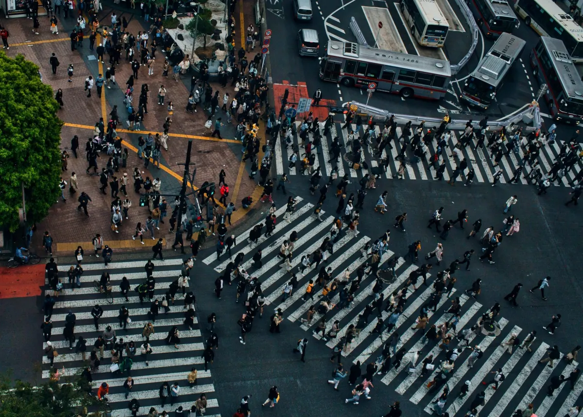 Pedestrians crossing a crowded city street, a picture of how a Bluesky block is a public record anyone can see.
