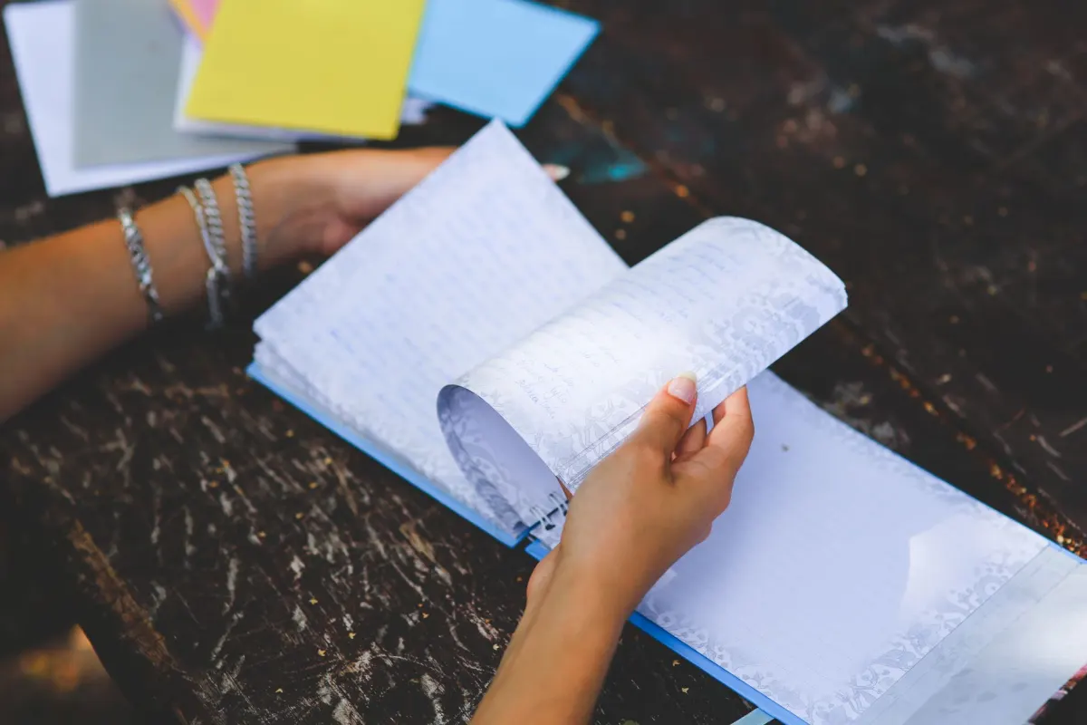 A person writing across several notebook pages, echoing how a long thought gets split into a chain of linked posts.