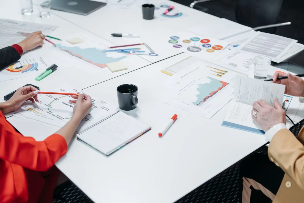 A small team reviews printed reports at a table, reflecting how a monitoring setup grows and gets organized over time.