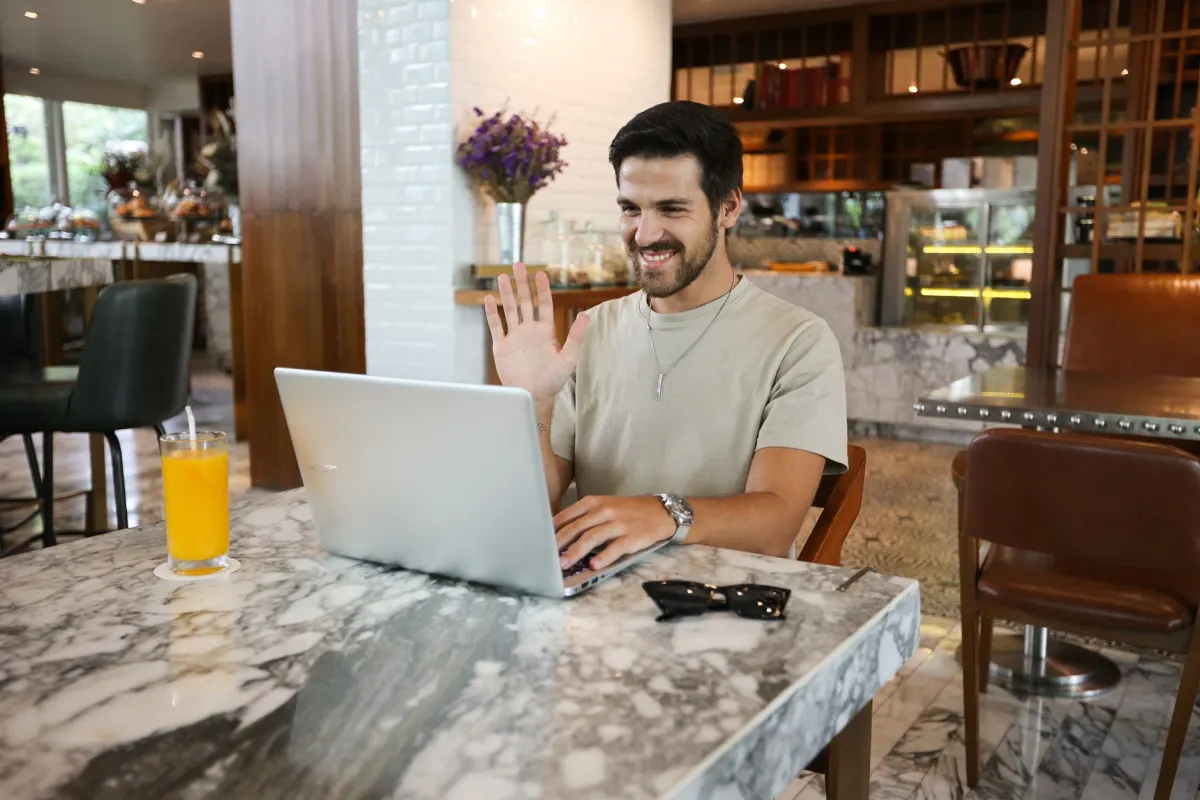 Una persona escribe en un portátil en una cafetería, donde ocurre gran parte de la participación en comunidades en línea.