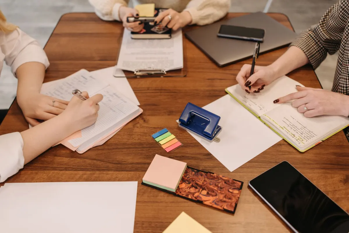 Une petite équipe examine des notes autour d'une table en planifiant de futurs sujets de blog.