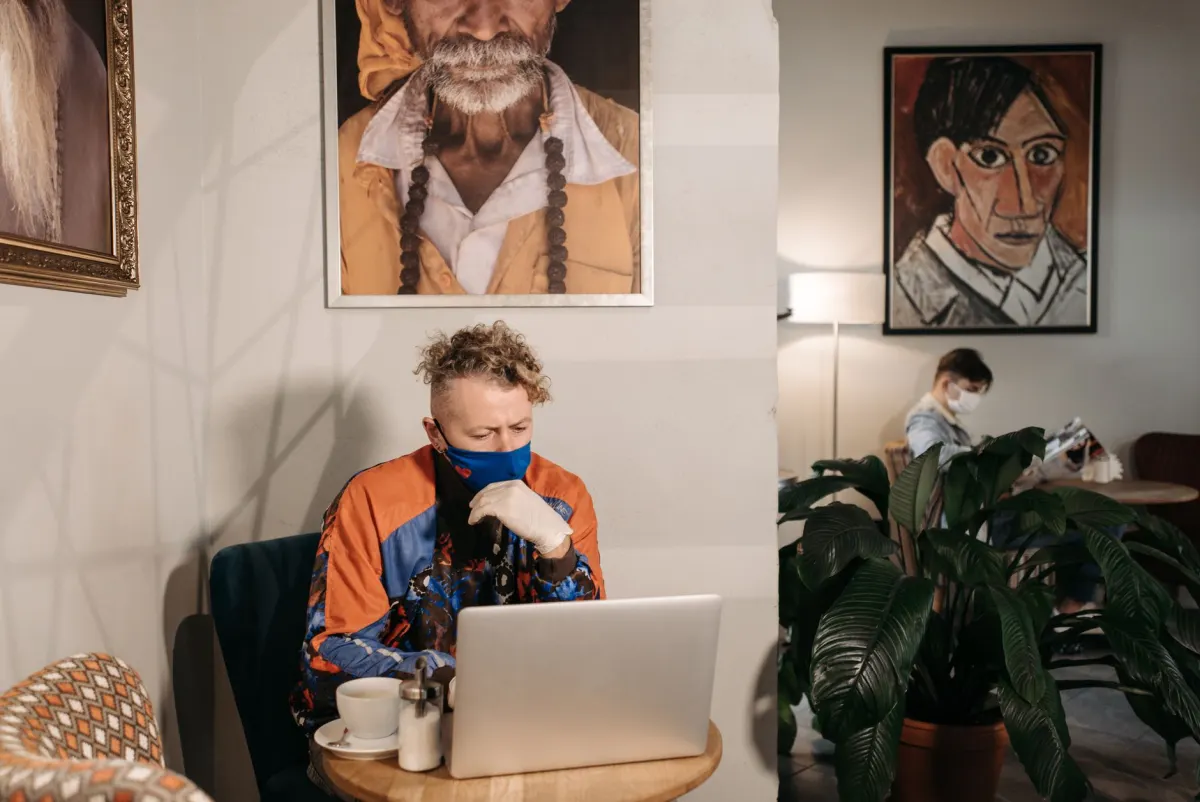 Eine Person liest in einem Café an einem Laptop, stellvertretend für Gespräche über eine Marke, die außerhalb ihrer eigenen Beiträge stattfinden.