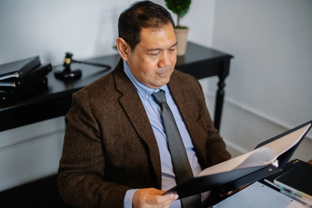 A manager reviewing papers at a desk, representing admins who approve anonymous posts before they go live.