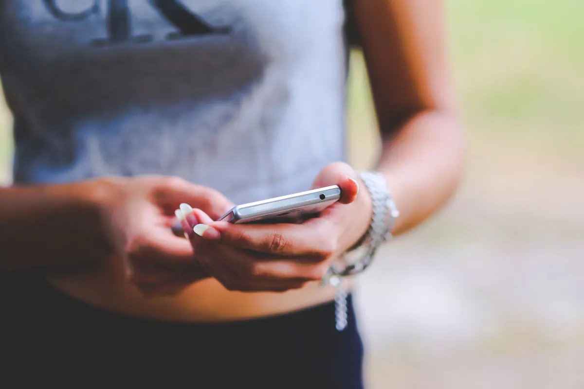 A woman scrolls a social feed on her phone, the kind of manual browsing that scraping automates in bulk.