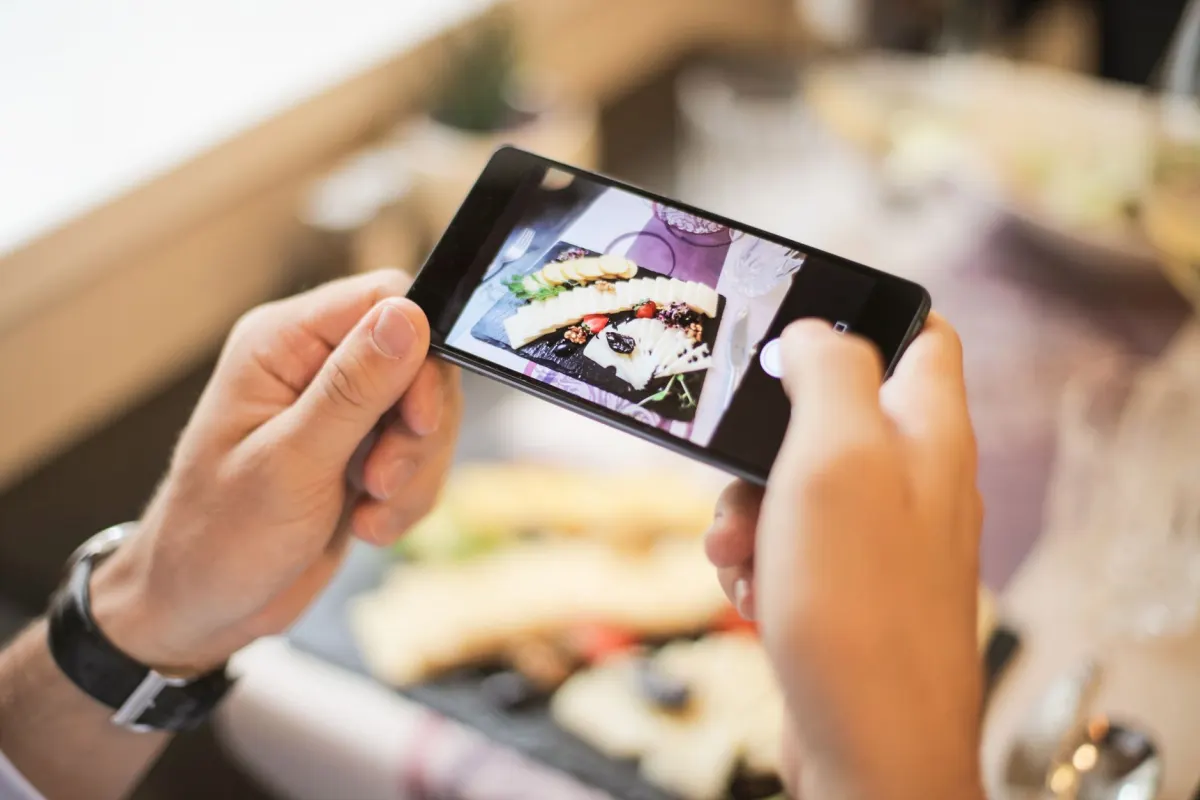 Ein Gast fotografiert einen Teller auf einem Restauranttisch, genau die unmarkierte Art von Beitrag, die reines Text-Monitoring nie erfasst.