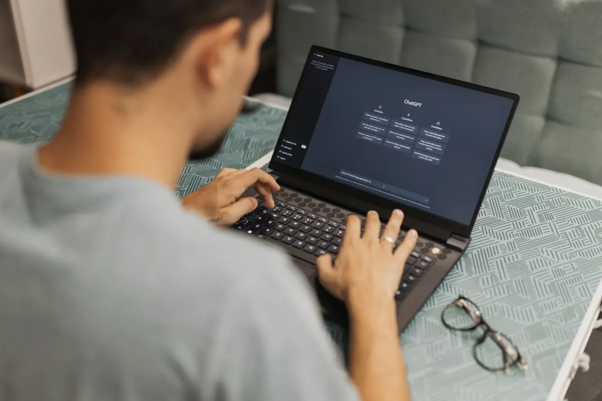 Una persona escribe una pregunta en un asistente de chat de IA en una laptop, el tipo de consulta que activa el proceso de descubrimiento y citación.