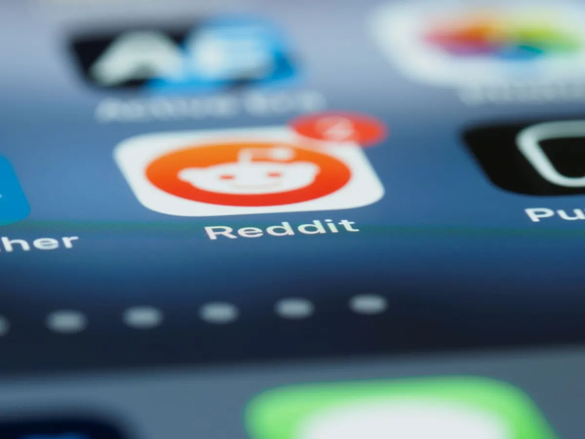Primer plano de una pantalla de teléfono mostrando un hilo de foro, el tipo de discusión comunitaria en la que se apoyan los modelos de IA para citar fuentes.
