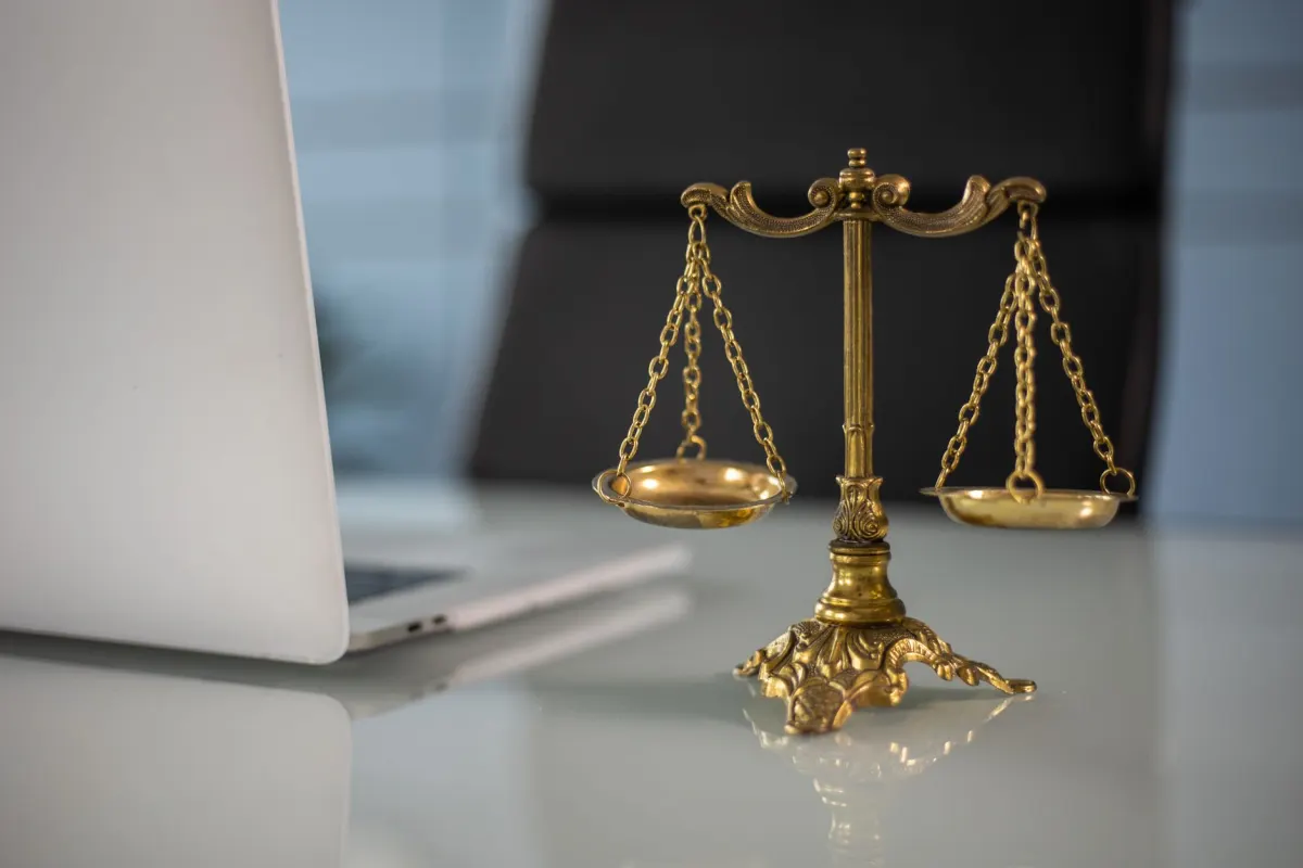 A laptop next to a small scale on a desk, representing the balance between a scrape and the terms of service it may breach.