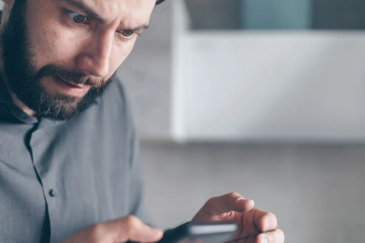 Quelqu'un fait défiler une longue liste de notifications sur son téléphone, la fatigue d'alerte que provoque un flux de surveillance encombré.