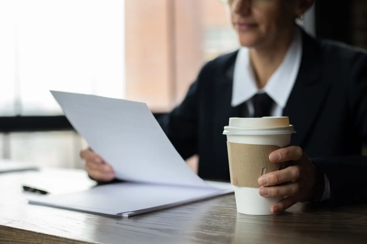 Person at a desk with coffee reading through a list on a laptop, like a daily Reddit digest checked each morning.