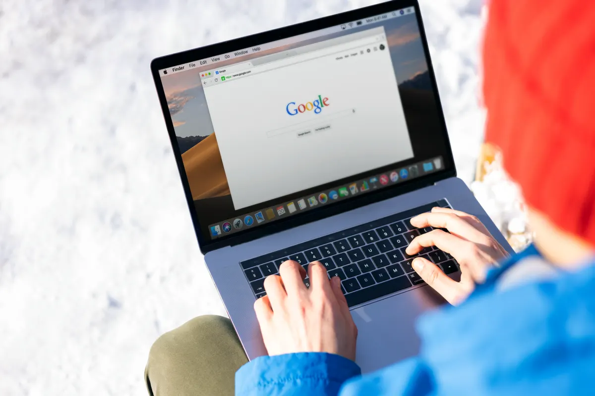 Eine Person tippt eine Suchanfrage in einen Laptop ein, sinnbildlich für den gezielten Einsatz von Suchoperatoren.